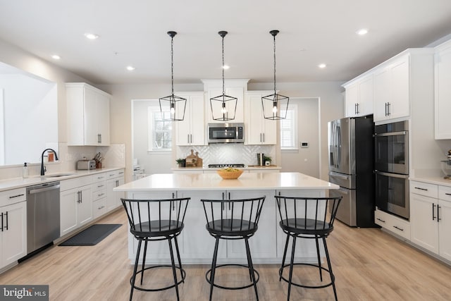 kitchen featuring sink, stainless steel appliances, pendant lighting, and a center island