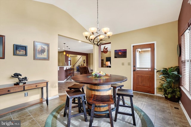 dining room featuring an inviting chandelier, vaulted ceiling, and tile patterned floors