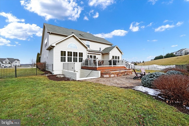 rear view of property with a deck, a patio area, and a lawn