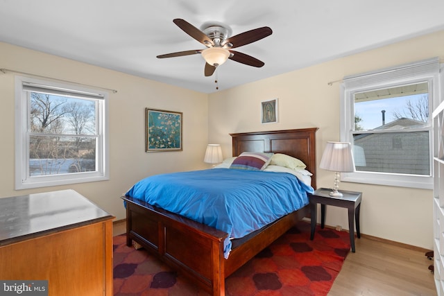 bedroom with multiple windows, light hardwood / wood-style flooring, and ceiling fan