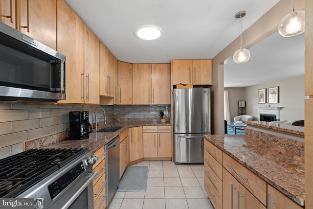 kitchen featuring pendant lighting, sink, stainless steel appliances, tasteful backsplash, and dark stone counters