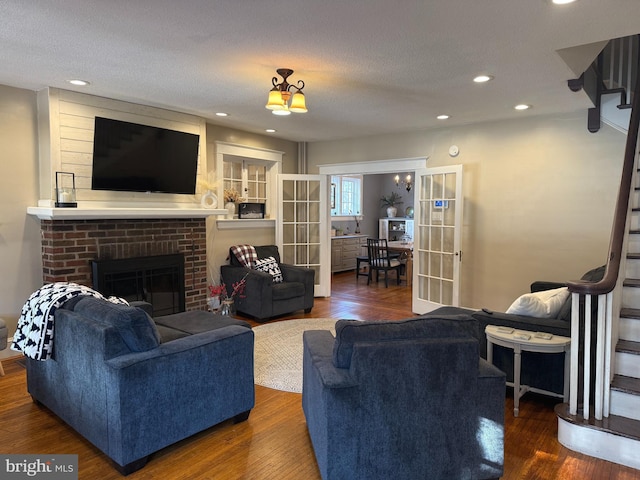 living room featuring a textured ceiling, a fireplace, dark hardwood / wood-style flooring, and french doors