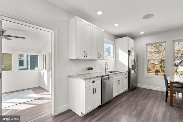 kitchen featuring sink, white cabinetry, light stone counters, dark hardwood / wood-style flooring, and stainless steel appliances