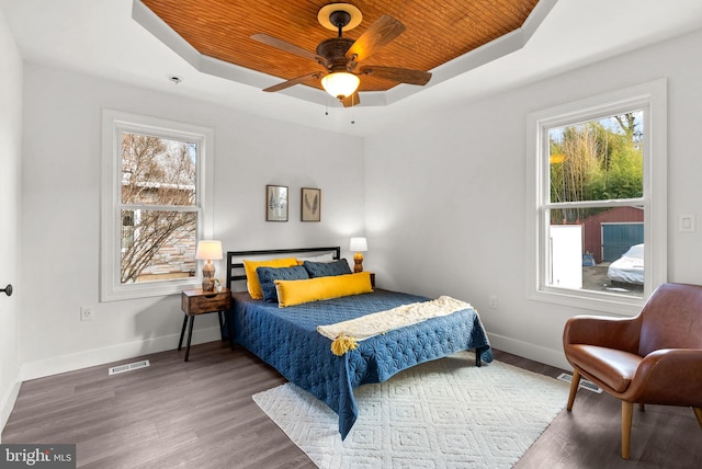 bedroom featuring hardwood / wood-style floors, wood ceiling, a raised ceiling, and ceiling fan