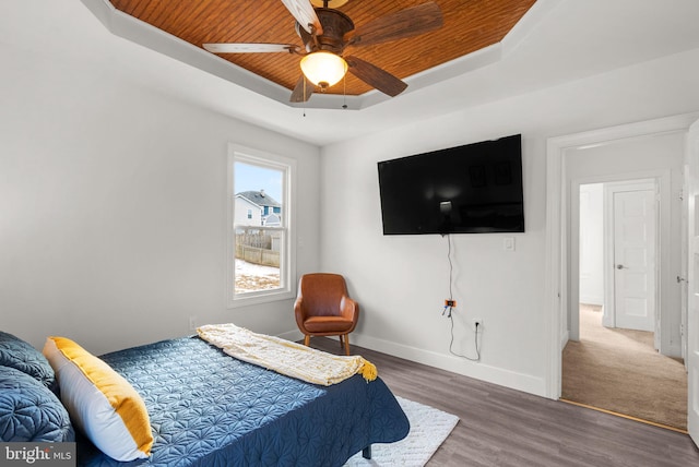 bedroom with hardwood / wood-style floors, wood ceiling, ceiling fan, and a tray ceiling