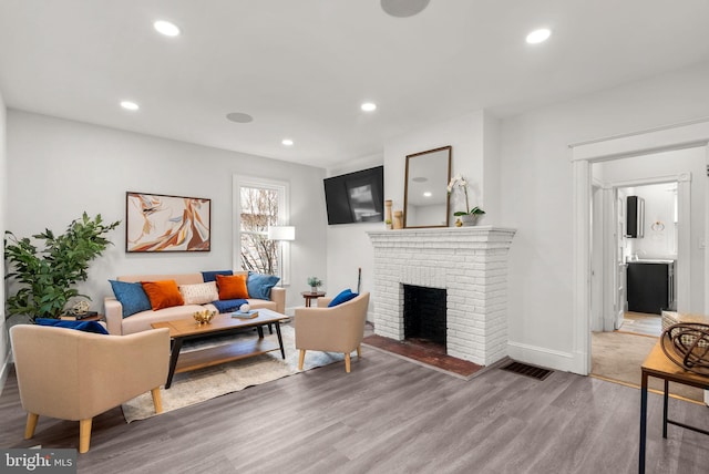 living room with wood-type flooring and a brick fireplace