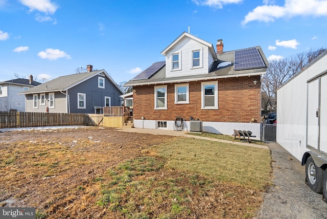 back of house with a lawn, cooling unit, and solar panels