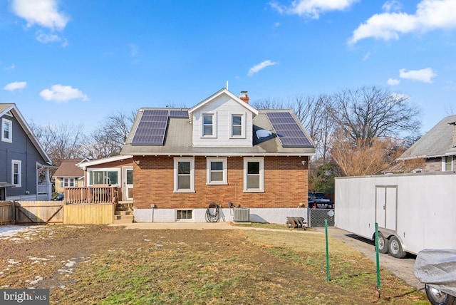 rear view of house with a yard, central AC, and solar panels