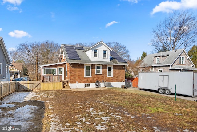 rear view of property featuring central AC unit and solar panels