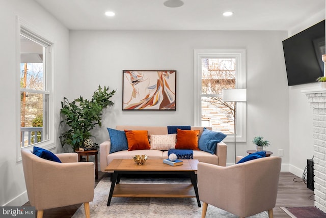 living room with wood-type flooring and a brick fireplace