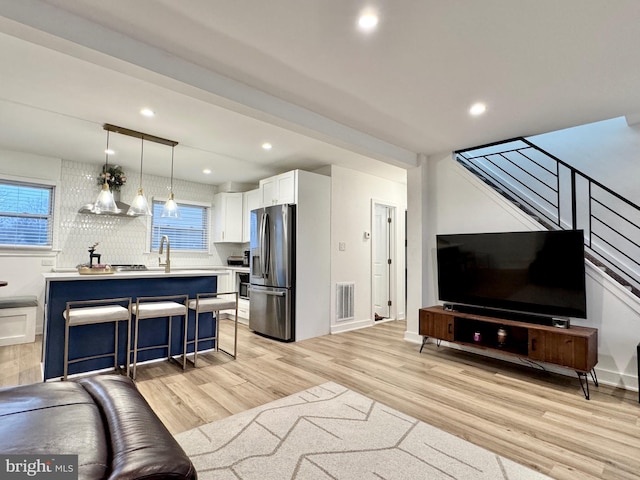 living room with beamed ceiling and light hardwood / wood-style flooring