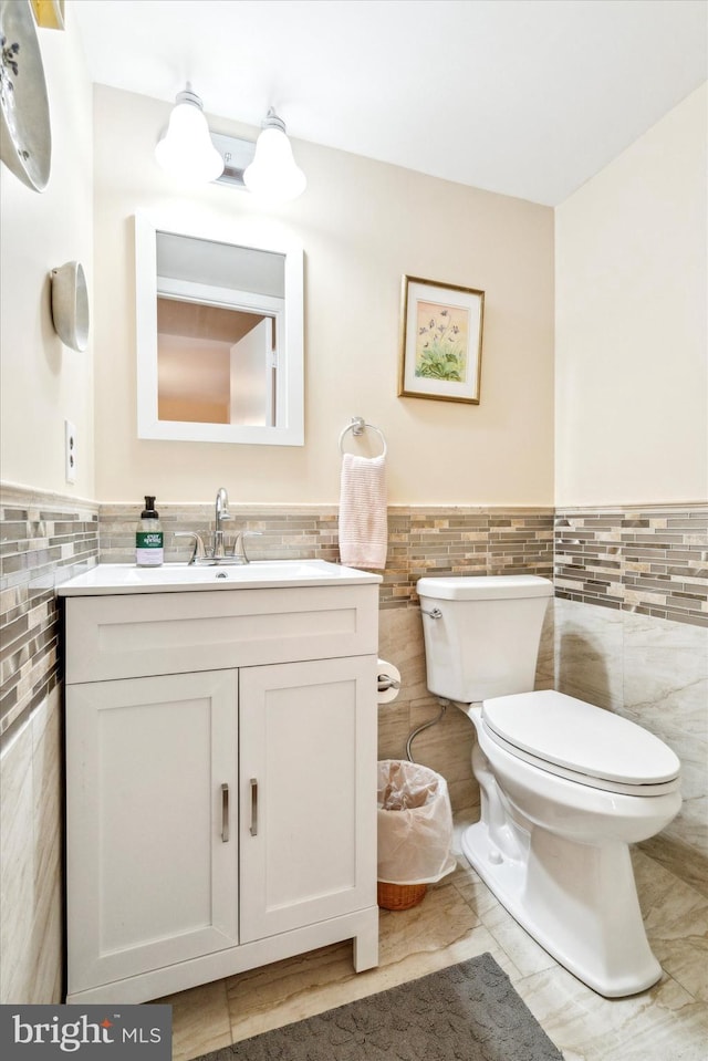 bathroom featuring vanity, toilet, and tile walls