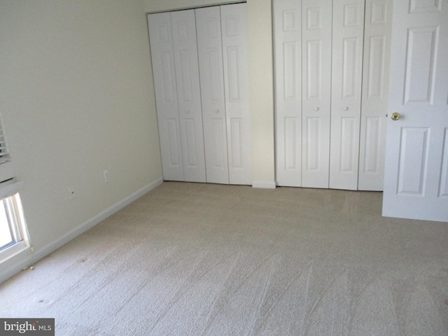 unfurnished bedroom with light carpet and two closets