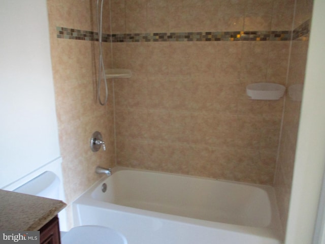 full bathroom featuring tiled shower / bath combo, vanity, and toilet