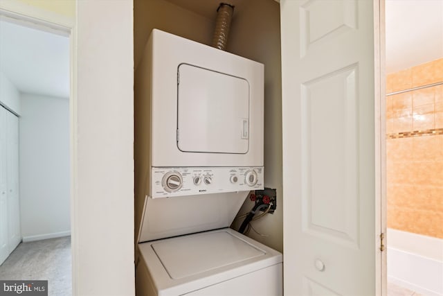 laundry area featuring light colored carpet and stacked washer / dryer