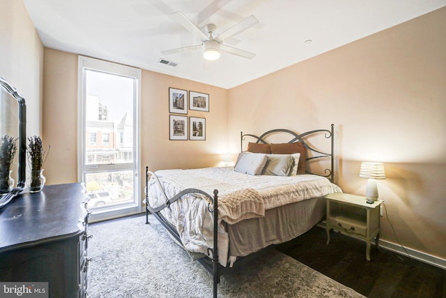 bedroom featuring a ceiling fan, visible vents, baseboards, and wood finished floors