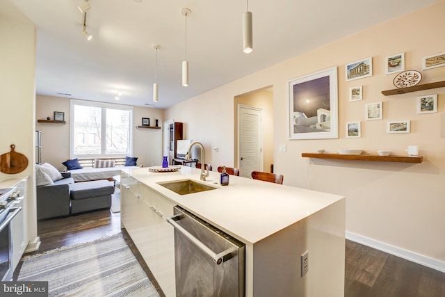 kitchen featuring appliances with stainless steel finishes, dark wood-type flooring, rail lighting, a kitchen island with sink, and a sink