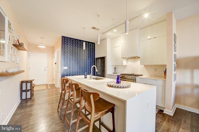 kitchen featuring high end stove, dark wood-type flooring, a sink, white cabinetry, and backsplash