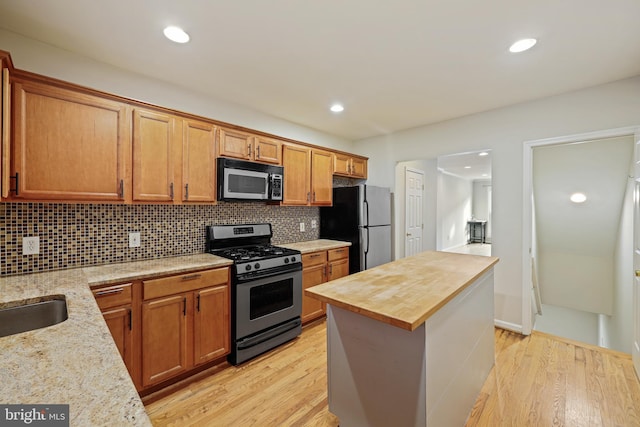 kitchen with appliances with stainless steel finishes, sink, backsplash, wooden counters, and light hardwood / wood-style floors