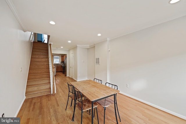 dining space with crown molding and light wood-type flooring