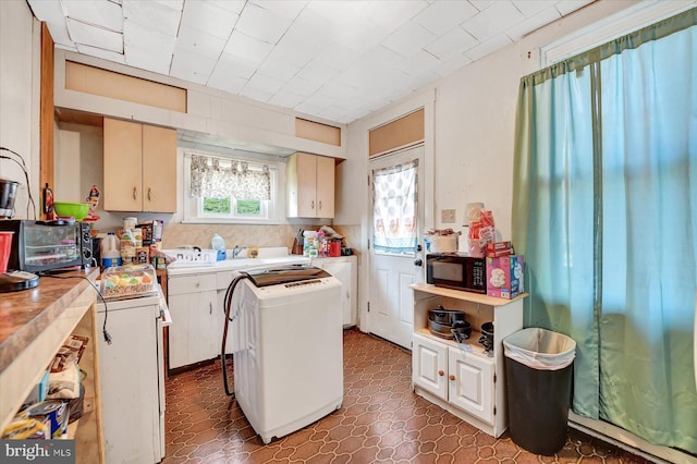 kitchen featuring a center island, washer / dryer, cream cabinetry, and dark tile patterned floors