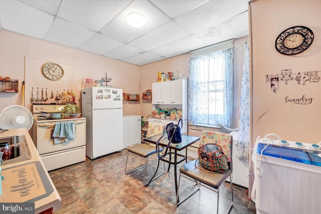 kitchen with white cabinets, white appliances, sink, and a drop ceiling