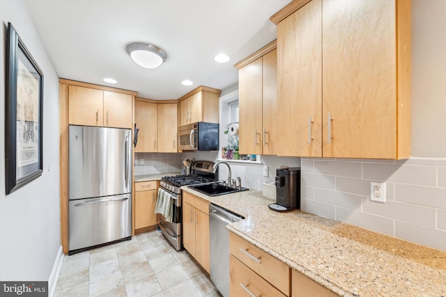 kitchen featuring sink, stainless steel appliances, light stone counters, decorative backsplash, and light brown cabinets