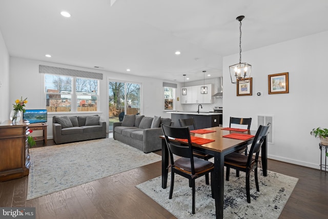 dining room featuring dark wood-type flooring, sink, and an inviting chandelier