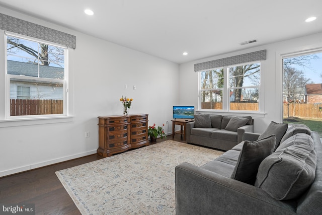 living room with dark wood-type flooring and plenty of natural light