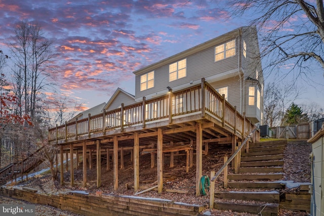 back of property at dusk with stairway, a wooden deck, and central AC unit