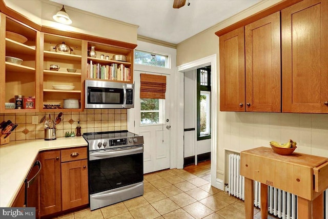 kitchen featuring radiator, light tile patterned floors, appliances with stainless steel finishes, ornamental molding, and decorative backsplash