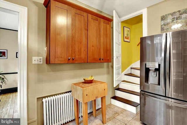 kitchen with stainless steel fridge with ice dispenser, radiator heating unit, and light tile patterned flooring