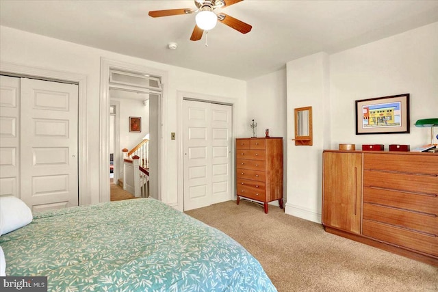 bedroom with two closets, light colored carpet, and ceiling fan