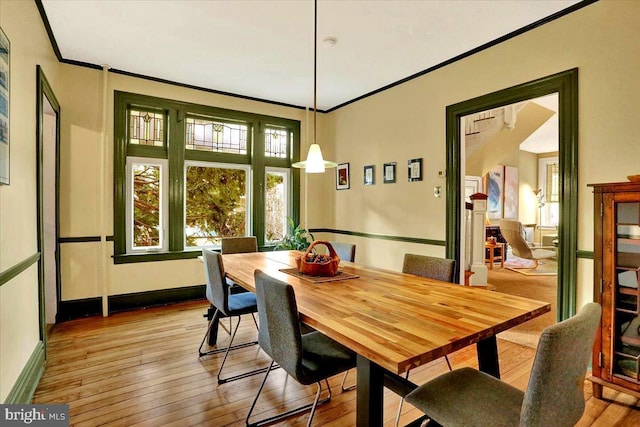 dining area with crown molding and light hardwood / wood-style flooring