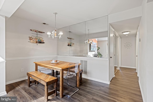 dining area featuring dark wood-type flooring and an inviting chandelier