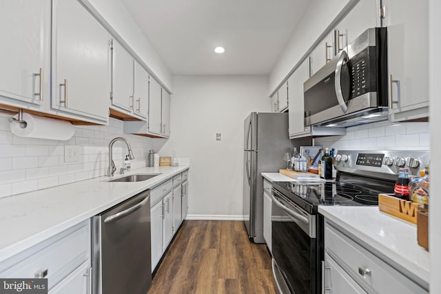 kitchen featuring dark wood-type flooring, sink, white cabinetry, tasteful backsplash, and appliances with stainless steel finishes