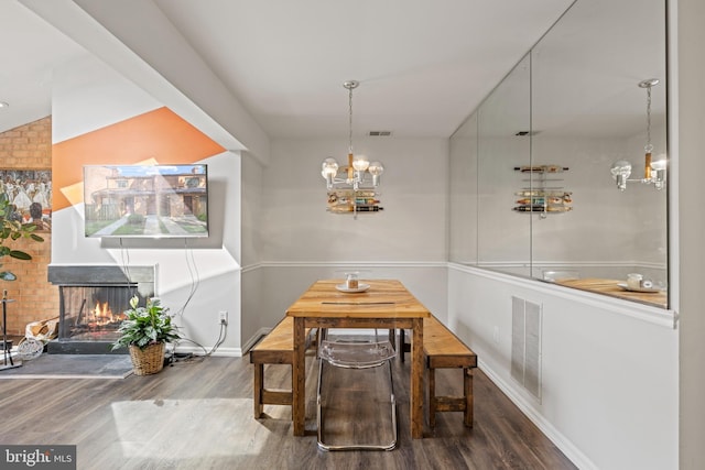 dining room featuring a multi sided fireplace, hardwood / wood-style floors, and an inviting chandelier