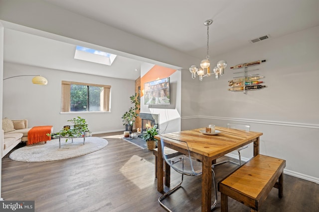 dining area with hardwood / wood-style flooring and vaulted ceiling with skylight