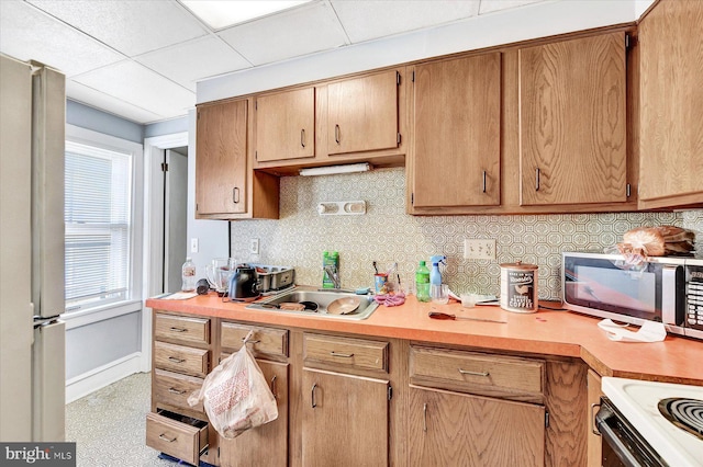 kitchen featuring a drop ceiling, sink, decorative backsplash, and fridge