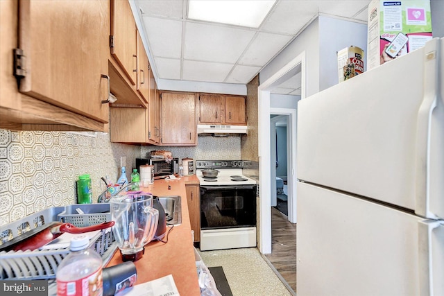 kitchen featuring white refrigerator, a paneled ceiling, decorative backsplash, and electric range oven