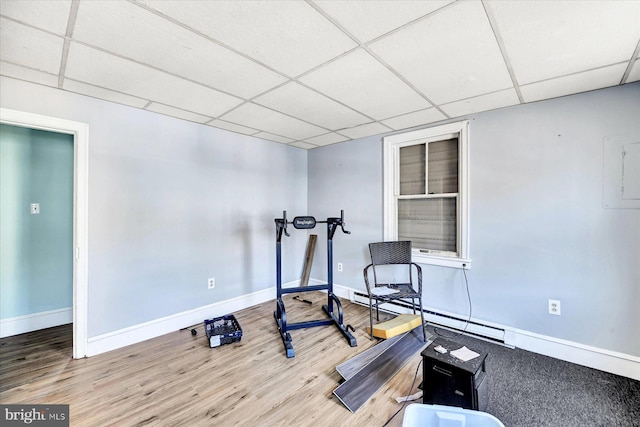 workout room with wood-type flooring, a drop ceiling, and a baseboard radiator