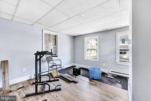 exercise area with a drop ceiling, hardwood / wood-style flooring, and a baseboard radiator