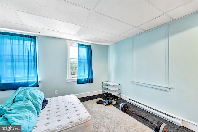 carpeted bedroom with a paneled ceiling and baseboard heating