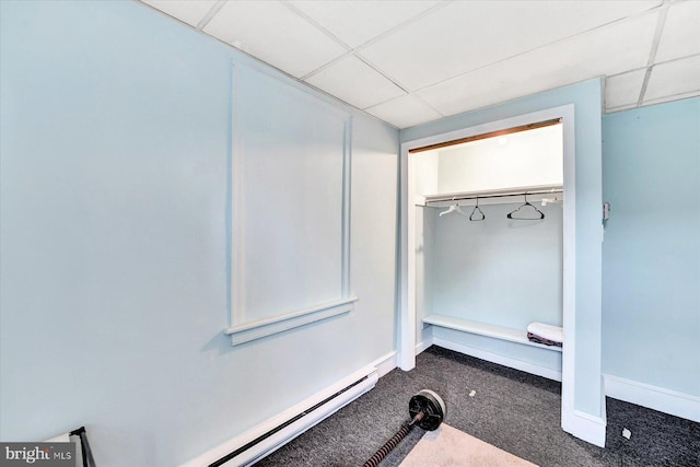 interior space featuring a drop ceiling, dark carpet, and a baseboard radiator