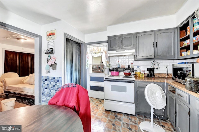 kitchen featuring white electric range oven, gray cabinets, and backsplash