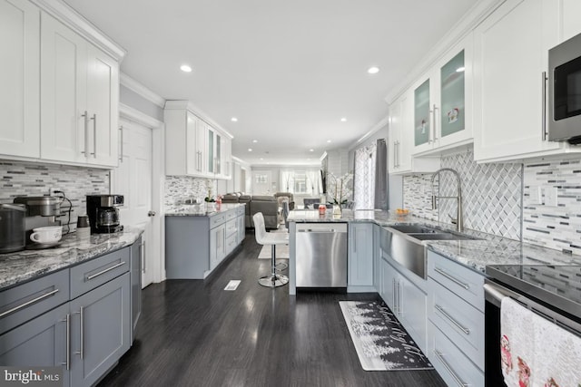 kitchen with white cabinetry, appliances with stainless steel finishes, sink, and light stone counters