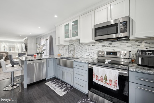 kitchen with white cabinetry, sink, decorative backsplash, light stone counters, and stainless steel appliances