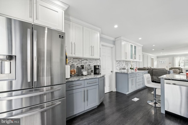 kitchen with gray cabinets, white cabinetry, backsplash, stainless steel appliances, and light stone countertops