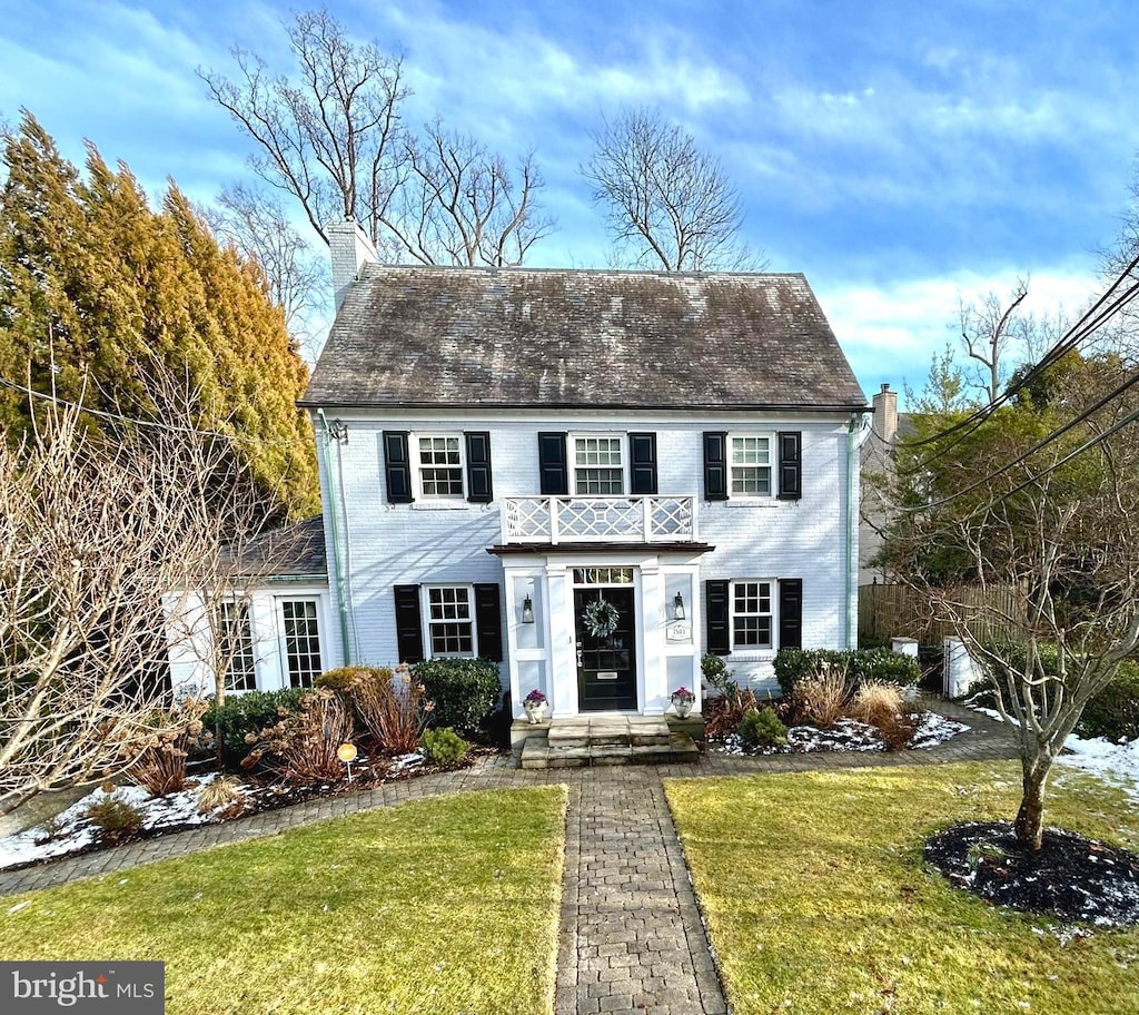 view of front of house with a balcony and a front lawn