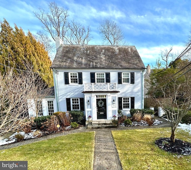 view of front of house with a balcony and a front lawn